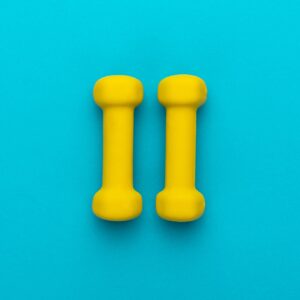 Photo Of Yellow Fitness Dumbells Over Blue Backgound With Central Composition