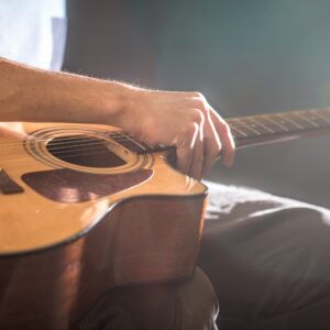 man sitting with an acoustic guitar, close-up, flash of light, a beautiful light in the background