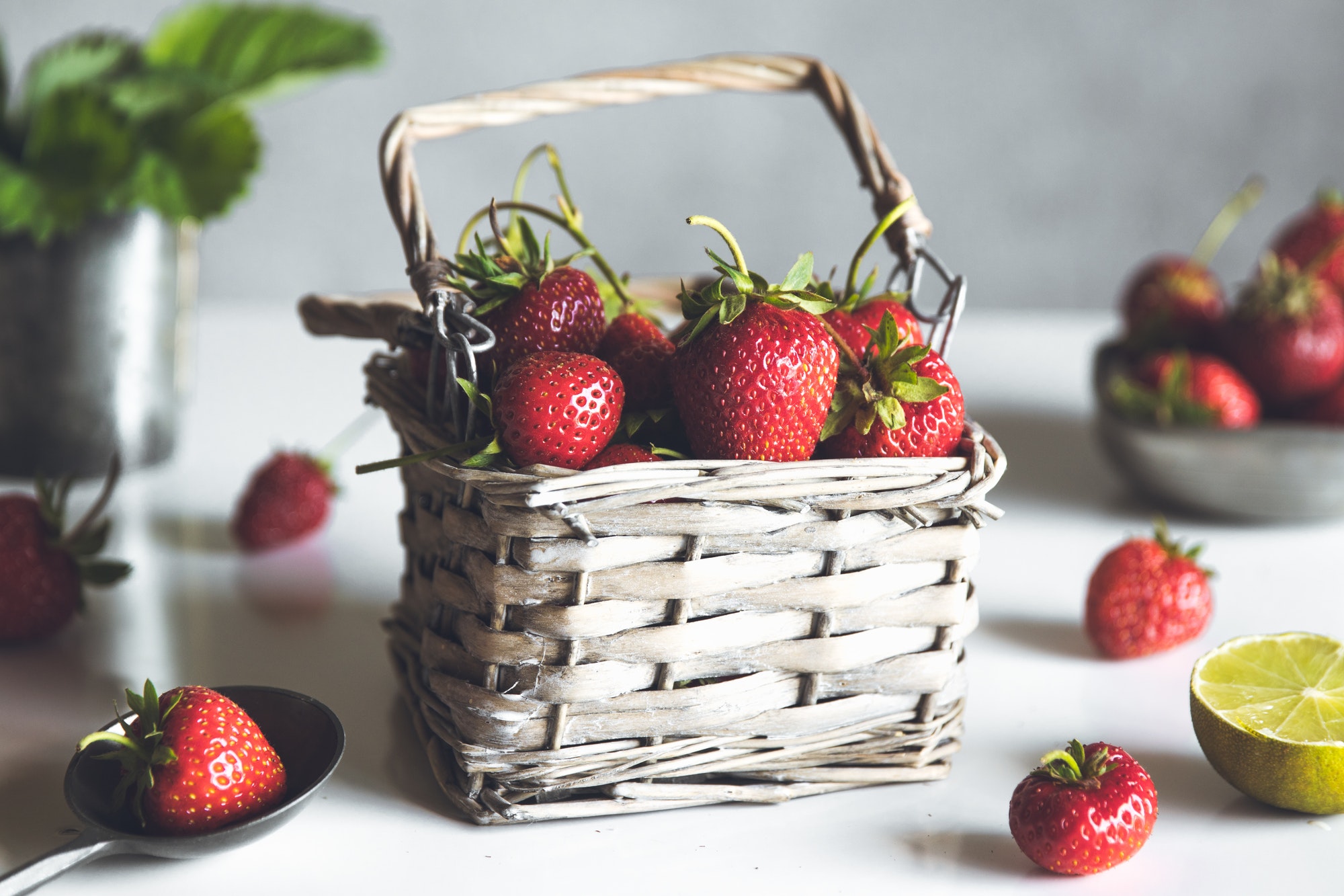 fresh strawberries in a basket on a white wooden table