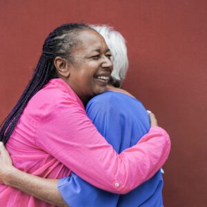 Old multiracial women meet and hugging each other with red background