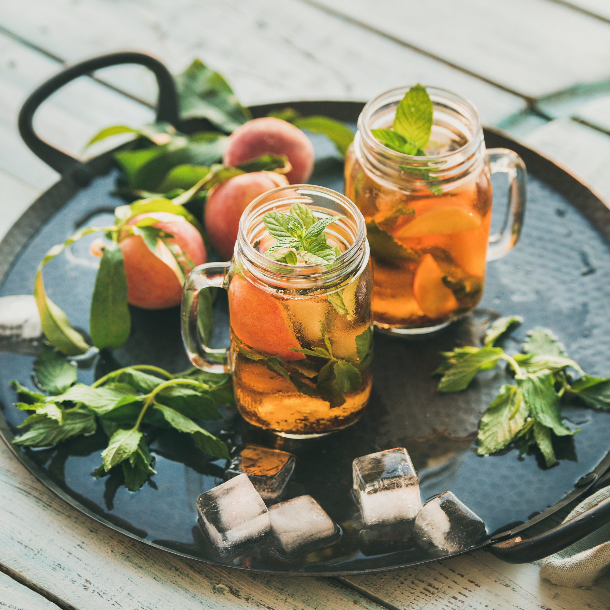 Summer refreshing cold peach ice tea on tray, square crop