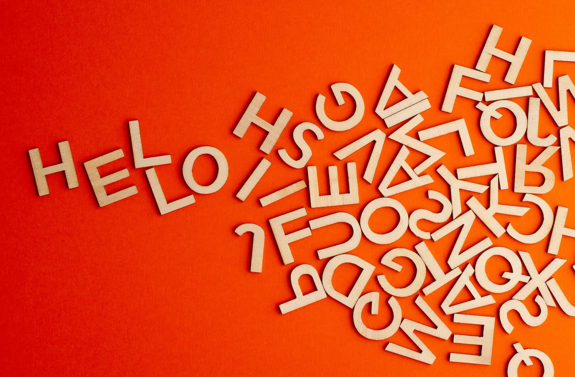 wooden cut alphabet letters on orange background spelling the word hello