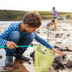 Children With Pet Dog Looking In Rockpools On Winter Beach Vacation