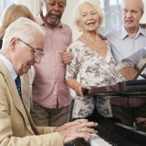 Group Of Seniors Standing By Piano And Singing Together