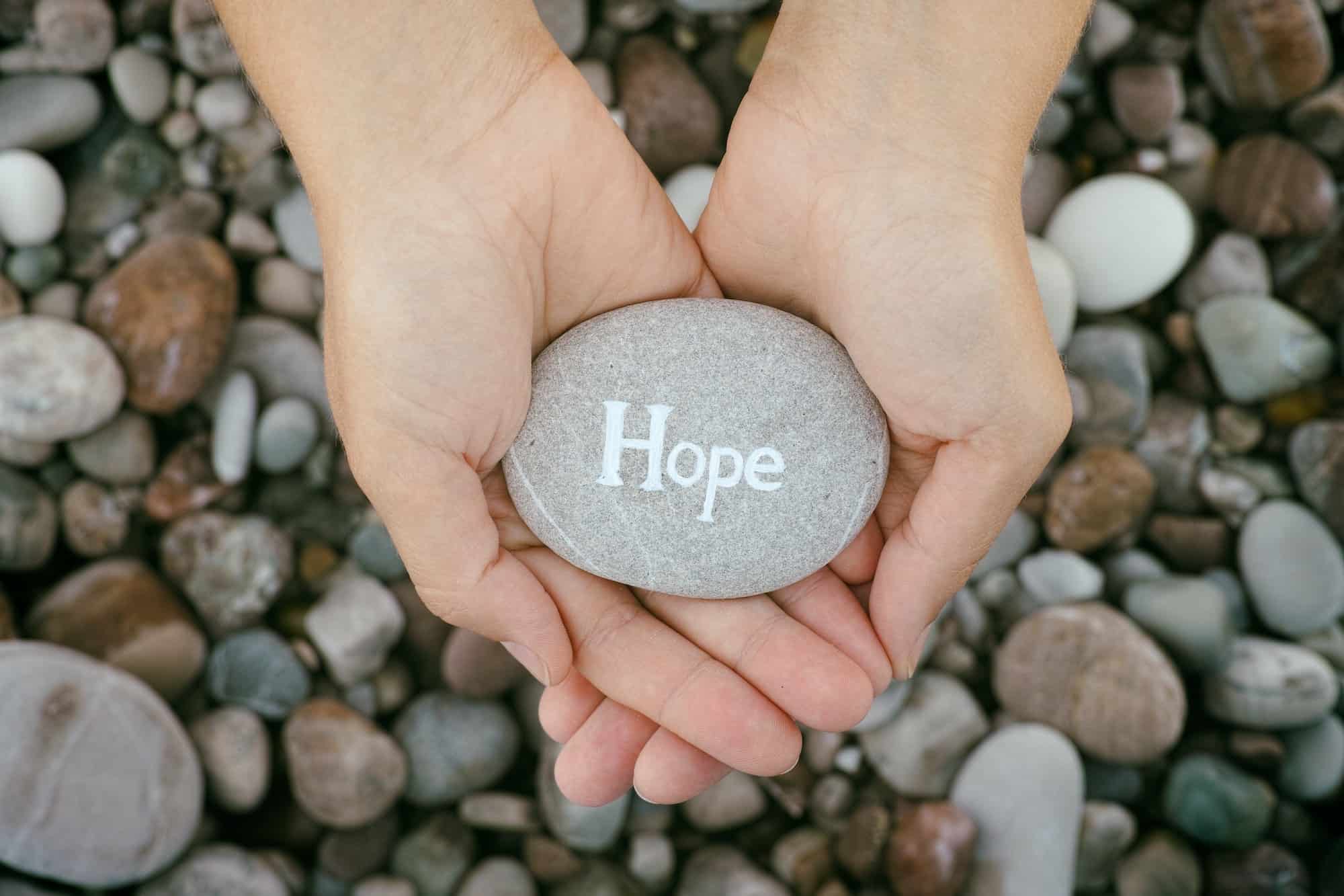 Woman holding stone with the word Hope in her palms