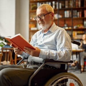 Adult disabled man in wheelchair reading a book
