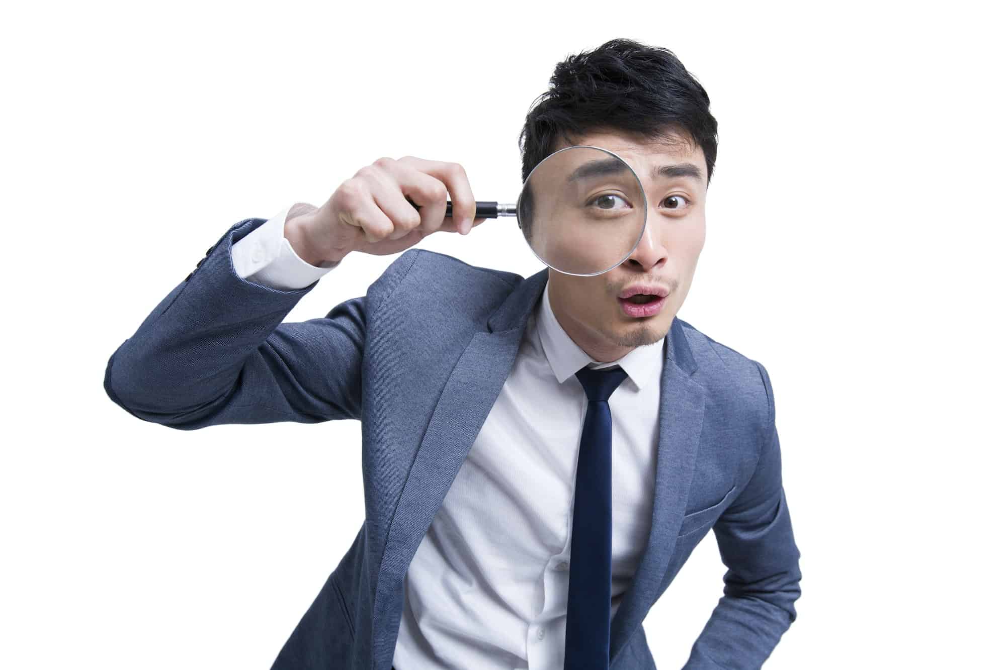 Young businessman looking through magnifying glass