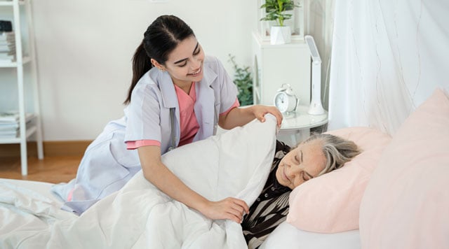 nurse supporting senior in long-term care bed